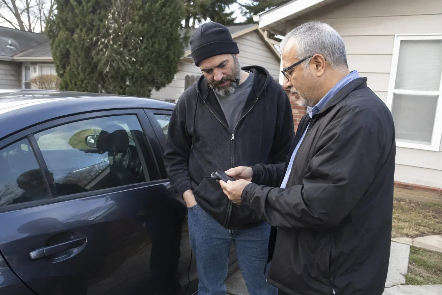 Two adults discussing a key fob beside a parked car. — Car Lockout Service, Aurora